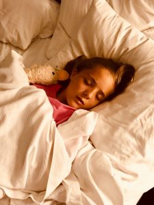 little girl sleeping in bed with her stuffed animal